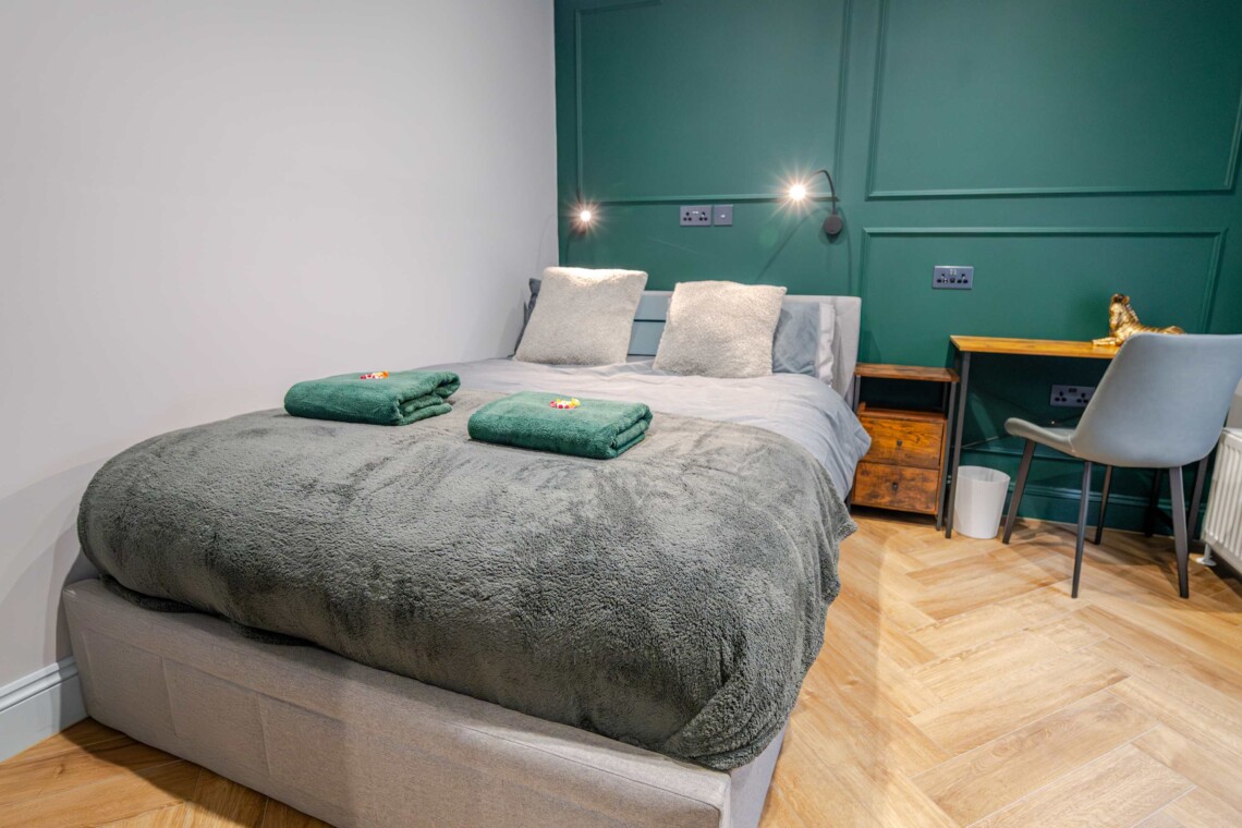The bedroom contains a double bed, offering a comfortable and restful retreat, complete with bedside tables and reading lamps for added convenience. 