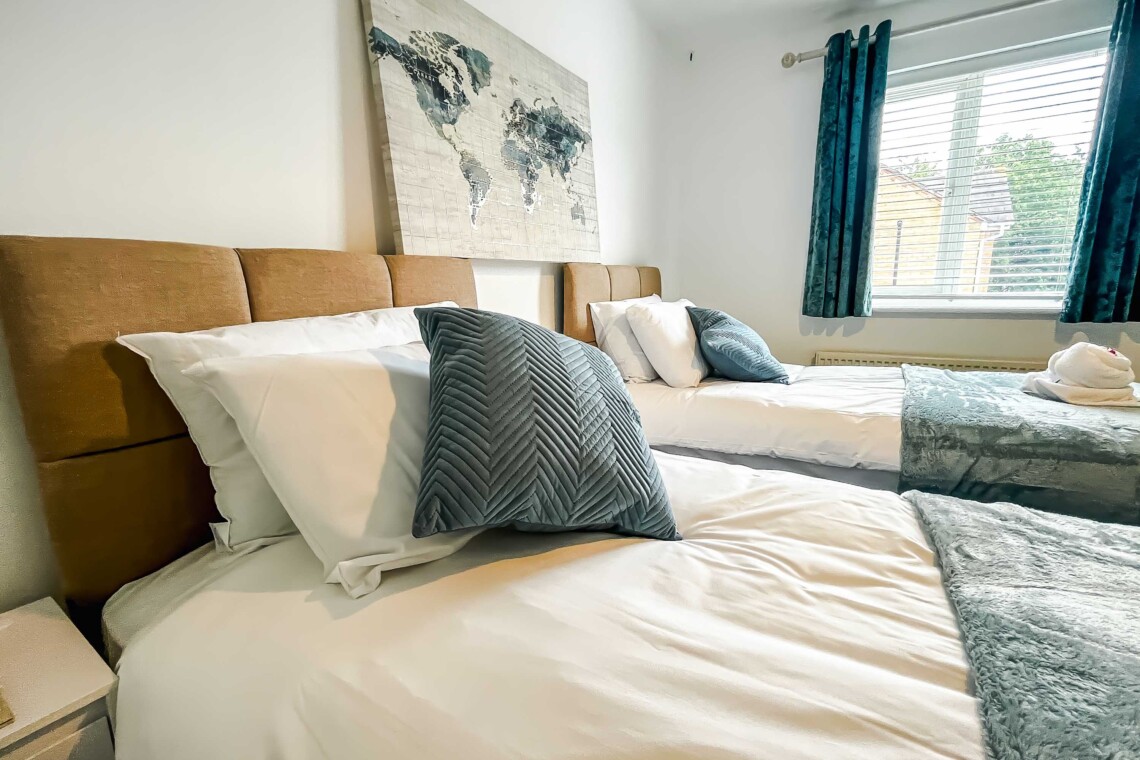 Bedroom two features two cosy single beds dressed with plush pillows and comfortable cushions. A bright, inviting space that is absolutely perfect for children and friends