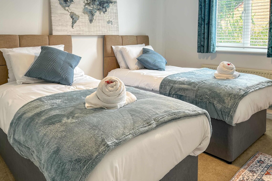 Bedroom two features two cosy single beds dressed with plush pillows and comfortable cushions. A bright, inviting space that is absolutely perfect for children, friends, or solo travellers