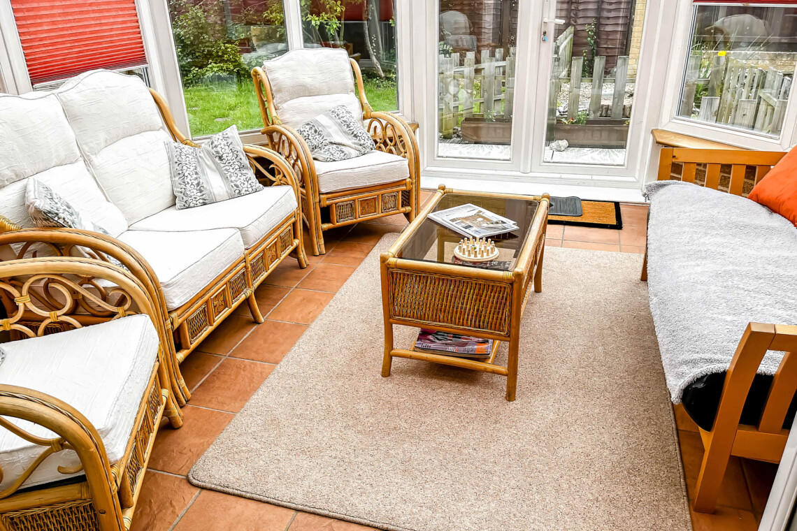 A light-filled conservatory with classic wicker armchairs with plush cushions for pure relaxation