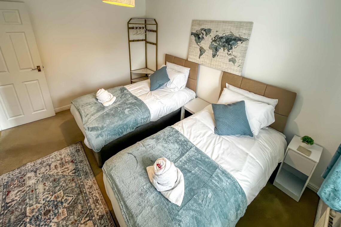 Bedroom two features two cosy single beds dressed with plush pillows and comfortable cushions. A bright, inviting space that is absolutely perfect for children, friends, or solo travellers