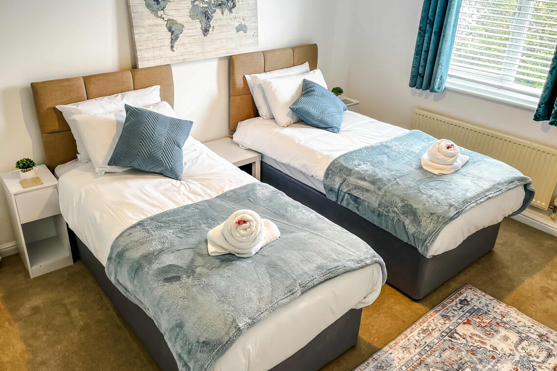 Bedroom two features two cosy single beds dressed with plush pillows and comfortable cushions. A bright, inviting space that is absolutely perfect for children, friends, or solo travellers