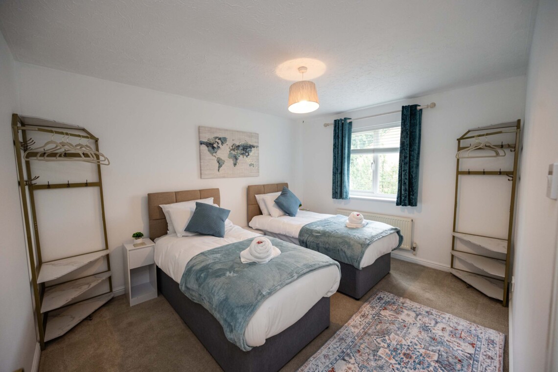 Bedroom two features two cosy single beds dressed with plush pillows and comfortable cushions. A bright, inviting space that is absolutely perfect for children, friends, or solo travellers