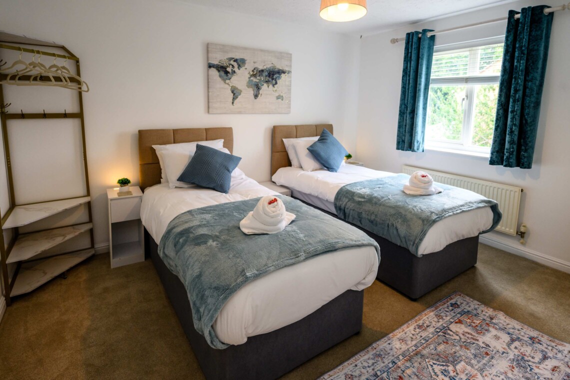 Bedroom two features two cosy single beds dressed with plush pillows and comfortable cushions. A bright, inviting space that is absolutely perfect for children, friends, or solo travellers